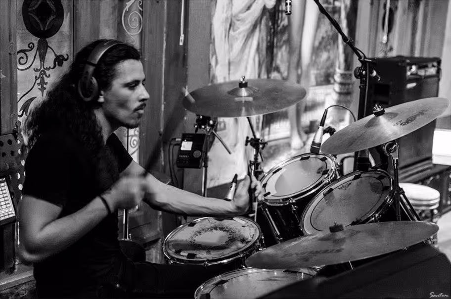 Alex passionately playing the drums on stage, immersed in the music at Ghost House.
